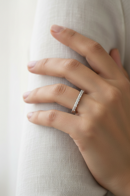 A silver band ring with a row of small clear stones, photographed on a plain white background.