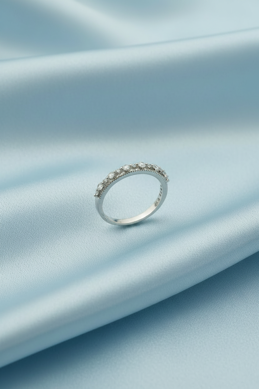 A silver band ring with a row of small clear stones, photographed on a plain white background.