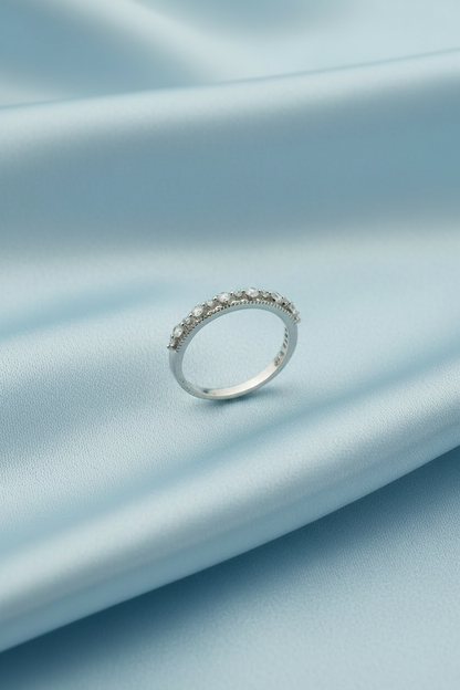 A silver band ring with a row of small clear stones, photographed on a plain white background.